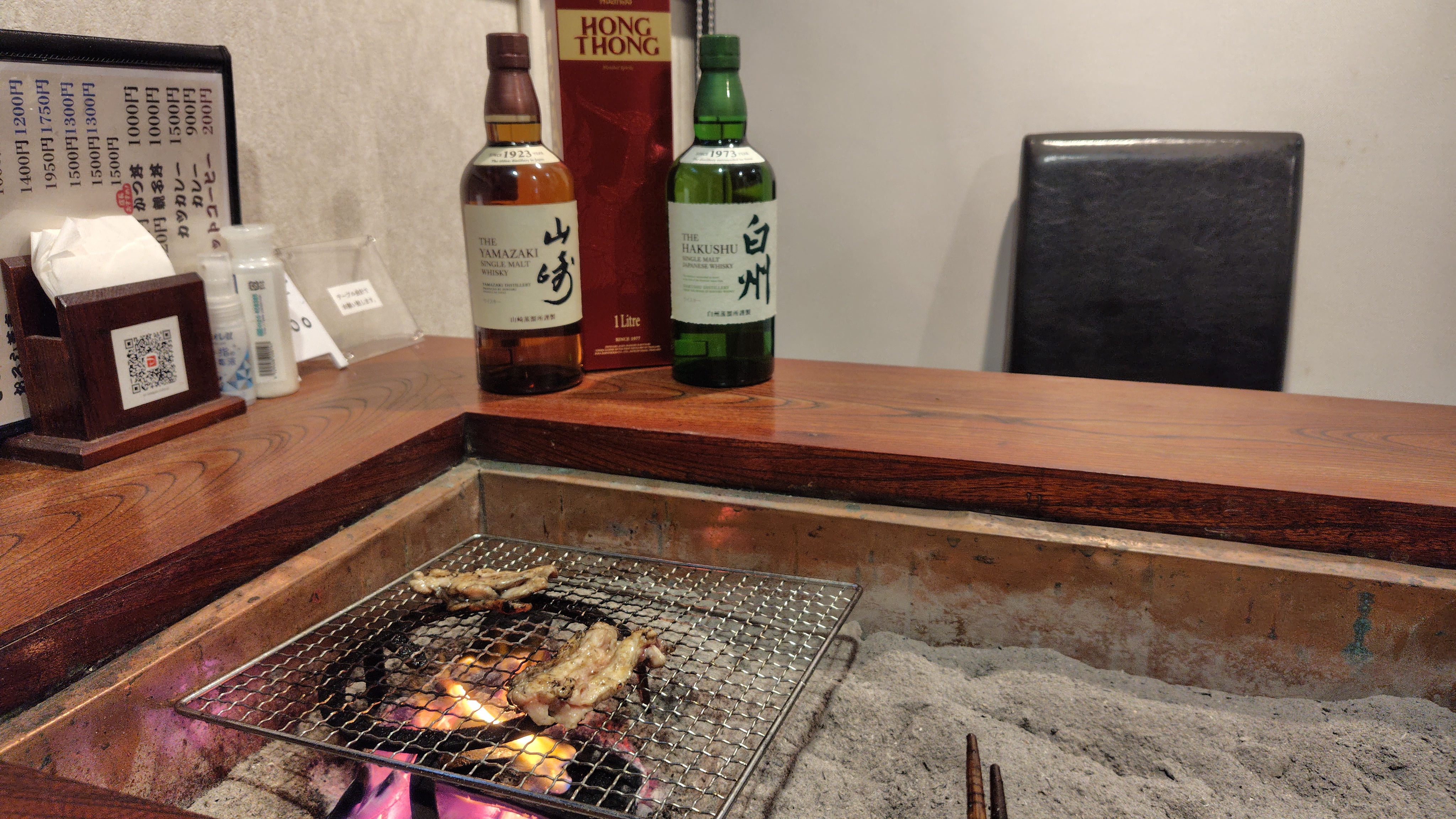 店内の七輪で焼かれている肉とカウンター